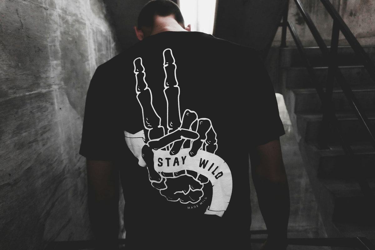 Person in a white and black t-shirt by a wall